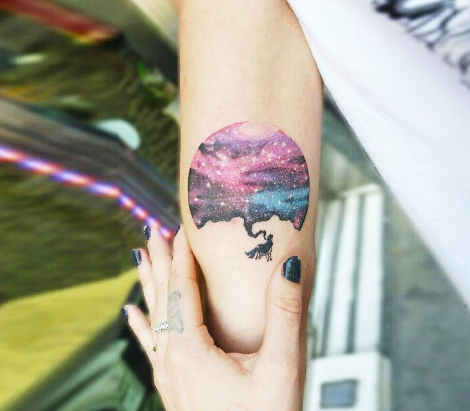 A sleeve tattoo of a galaxy with stars and a nebula