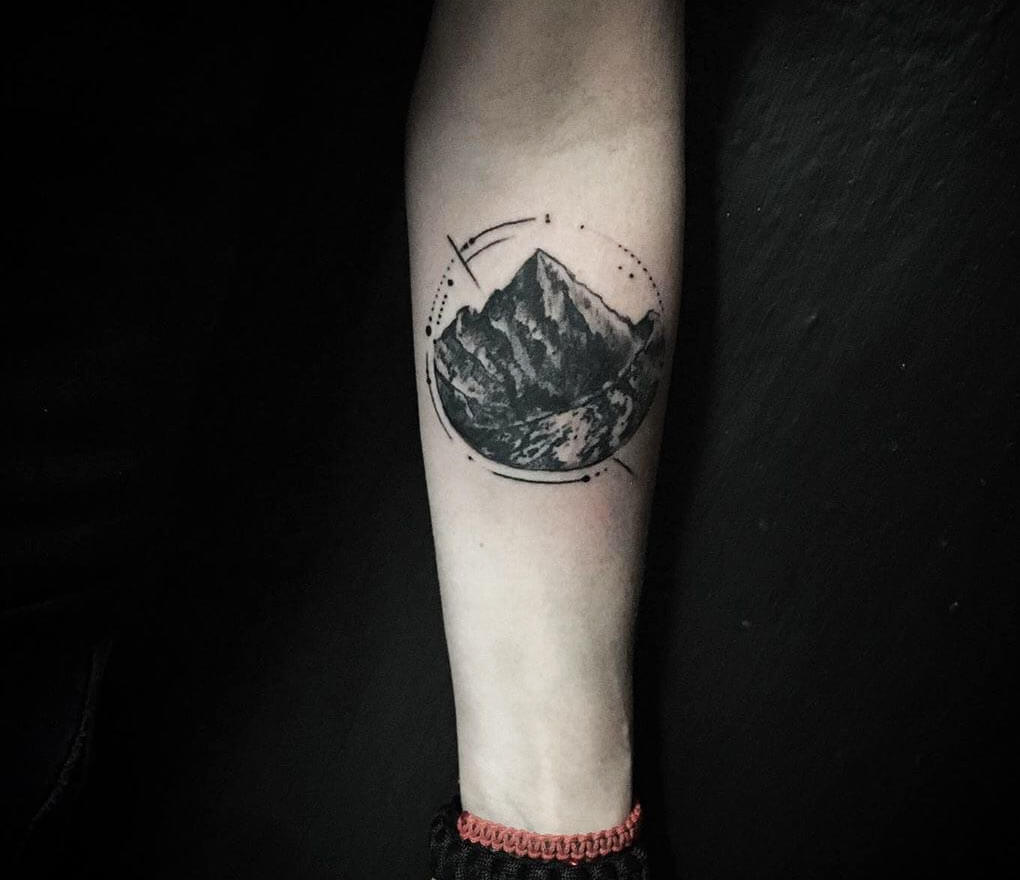 Heavenly landscape circle tattoo on the inner arm.