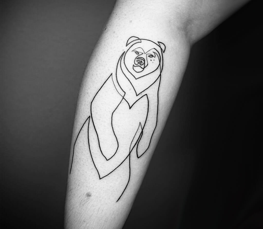 Micro-realistic teddy bear tattoo on the inner forearm.