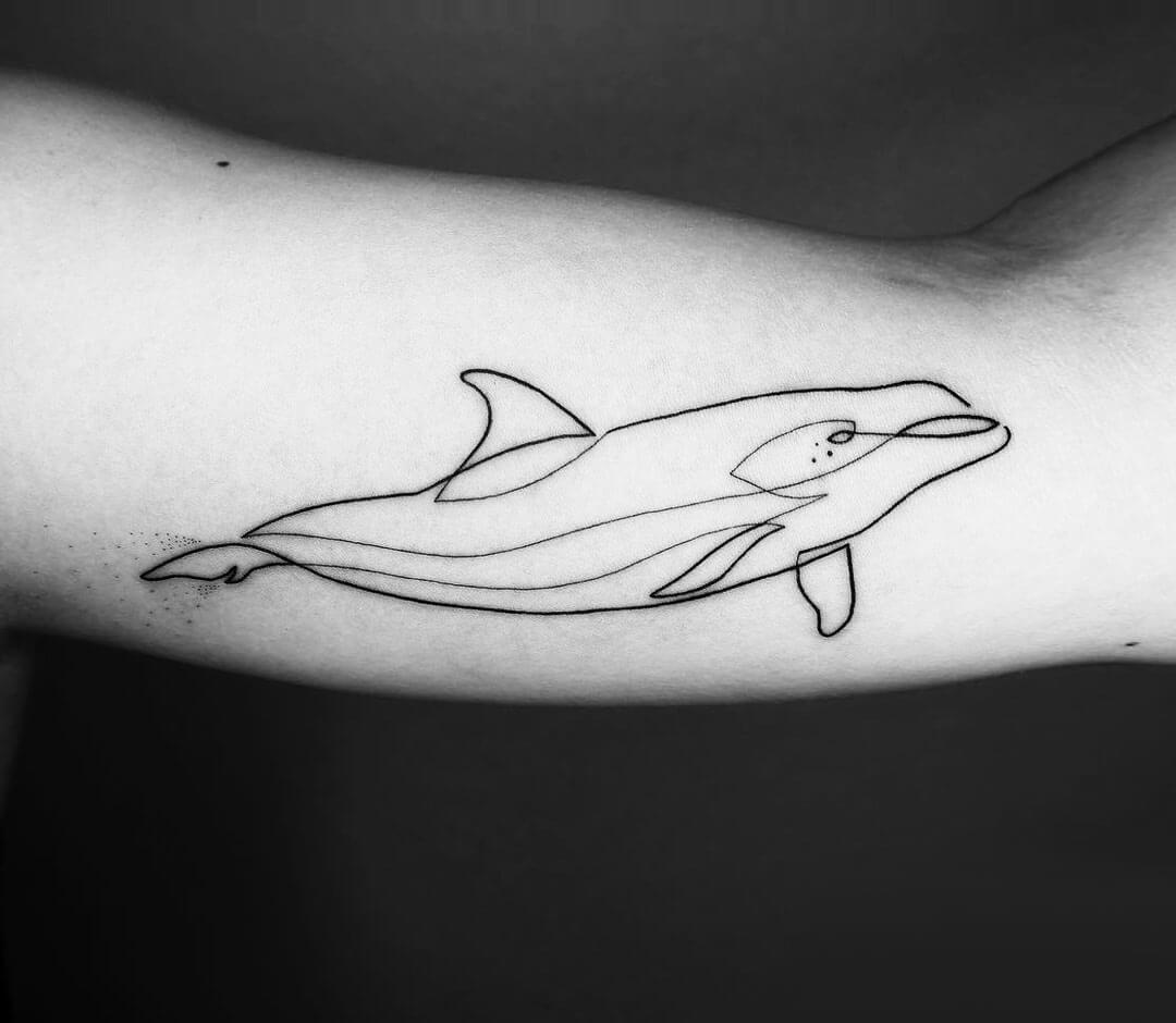 Tiny dolphin tattoo located on the ankle, minimalistic