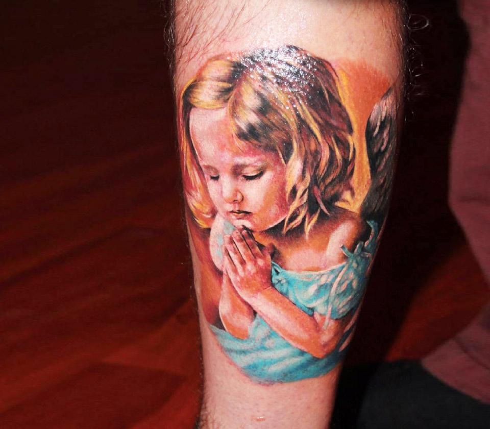 Minimalistic cherub tattoo located on the upper arm,
